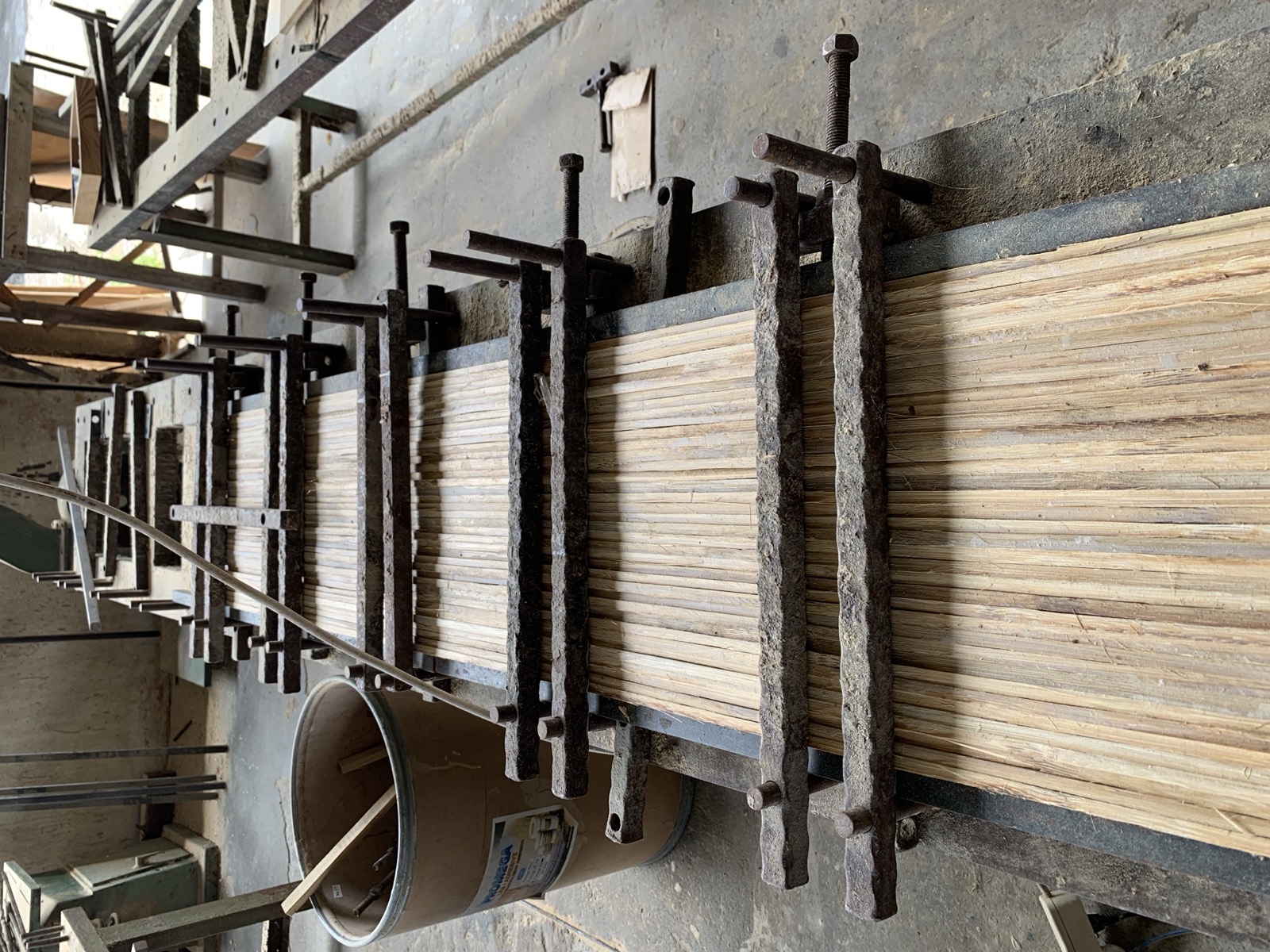 Glued bamboo strips clamped in steel presses to cure into a solid laminated bamboo panel